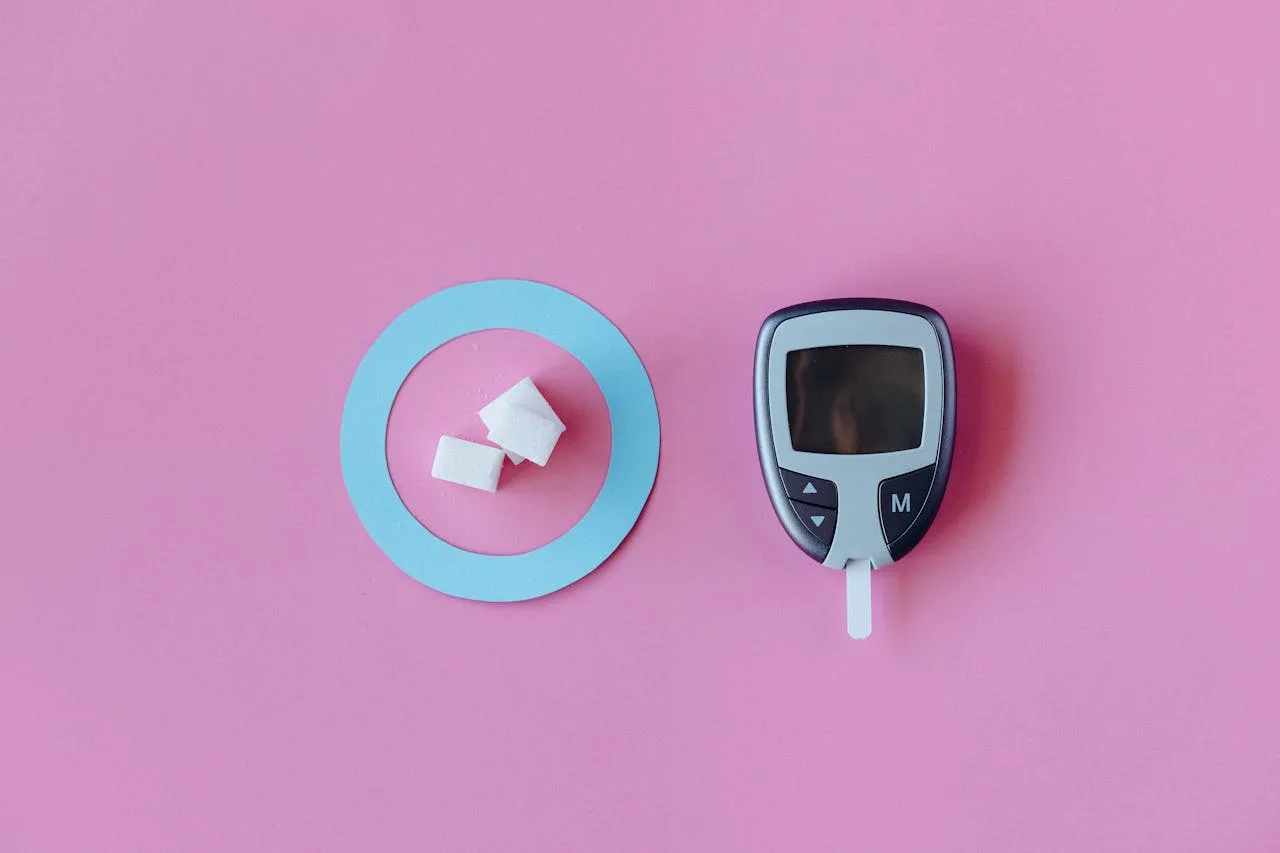 about-01 Flat lay of glucometer with sugar cubes on pink background, symbolizing diabetes awareness.